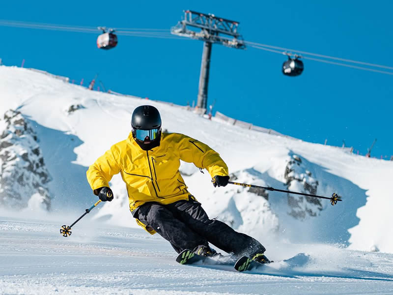 lyziar na svahu, vzadu vidno kabinky lanovky