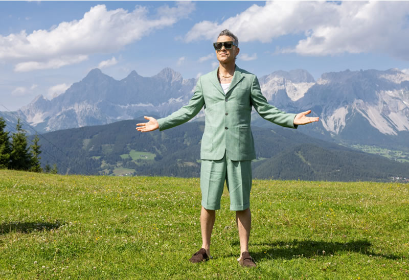 anglický spevák Robbie Williams na trave pred Alpami 