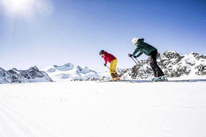 Tirolsko, ľadovec Pitztal v Rakúsku, dvaja lyžiari sa idú spustiť dolu kopcom